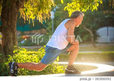Man Does Exercises Squats on Knee on Stone Barrier 36366092