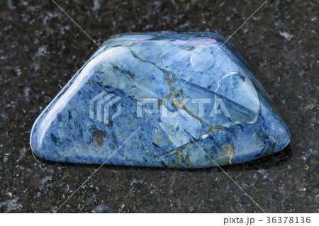 tumbled rhodusite gemstone on dark background 36378136