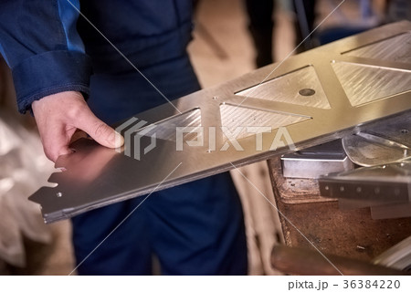 Hand holding metal part. 36384220