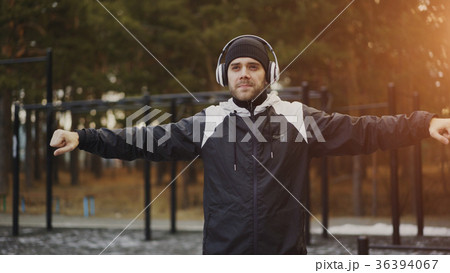Handsome man in headphones doing warm-up exercise 36394067