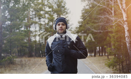 Attractive runner man in headphones jogging while Attractive runner man in headphones jogging while 36394085