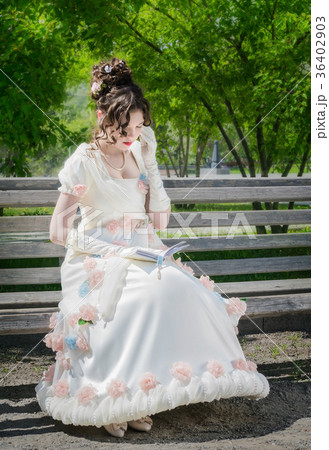 young woman is reading a book sitting on a bench. 36402903