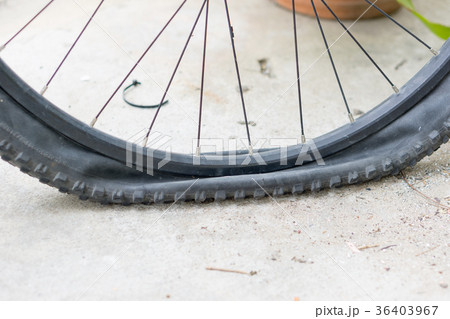 Bicycle wheel with flat tyre on the concrete road. 36403967