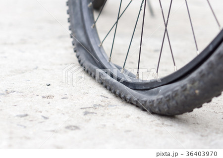 Bicycle wheel with flat tyre on the concrete road. 36403970