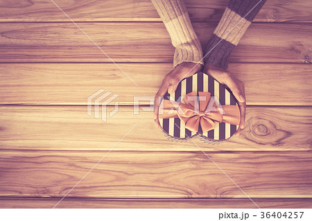 Hand holding heart gift box shape on wooden 36404257