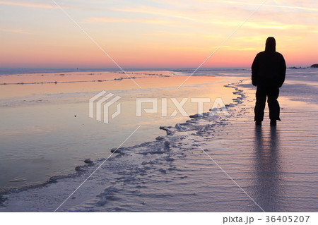 Man standing on the frozen river at sunset Man standing on the frozen river at sunset 36405207
