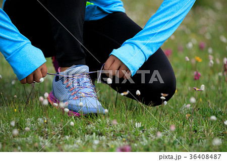 fitness woman runner tying shoelace on grassland fitness woman runner tying shoelace on grassland 36408487