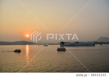 インド　ウダイプルのタージ・レイク・パレス　美しい夕日とピチョーラー湖　湖面を行き交う観光船　 36413155