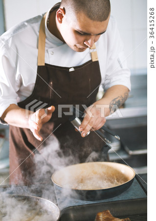 Young attractive male cook with uniform preparing Young attractive male cook with uniform preparing 36415268