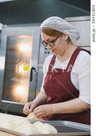 Adult woman in glasses and apron bakes cakes in 36441805