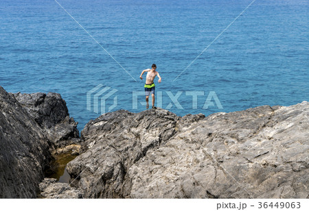 young man on a cliff getting out of balance 36449063