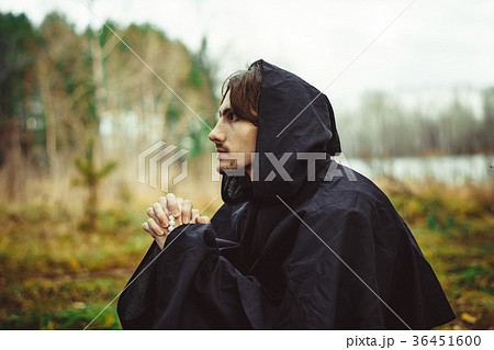 a monk in robes praying in the woods 36451600