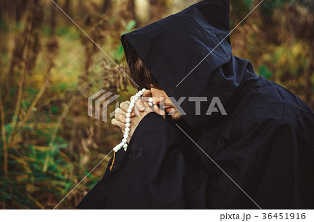 a monk in robes praying in the woods 36451916