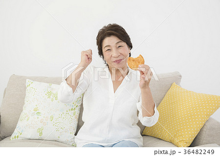 美味しそうにおせんべいを食べるシニア女性　歯の健康 36482249
