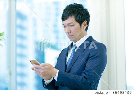 スマホを操作するビジネスマン　携帯電話　スマートフォン　中堅社員　ビジネスイメージ 36498439