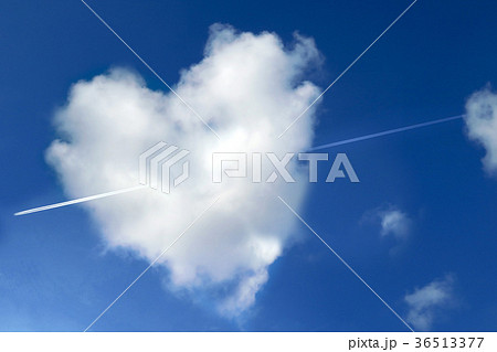 ハート型の雲を突き抜ける飛行機雲の写真素材