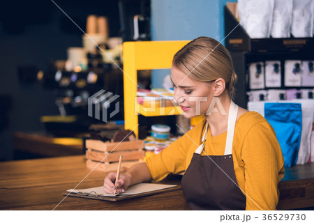 Cheerful barista making notes in confectionary Cheerful barista making notes in confectionary 36529730