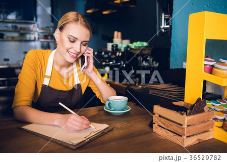 Cheerful woman writing and speaking by phone Cheerful woman writing and speaking by phone 36529782