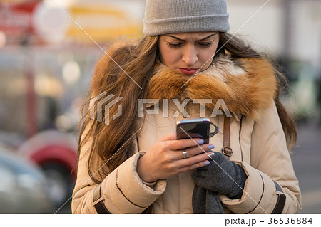 Girl walking and texting on the smartphone in the Girl walking and texting on the smartphone in the 36536884