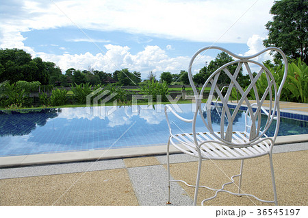 White chair next to open air swimming pool White chair next to open air swimming pool 36545197