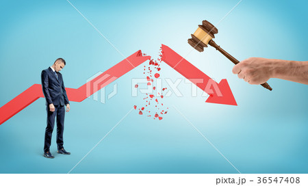 A small sad businessman stands near a red 36547408