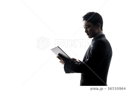 タブレットを見る男性シルエットの写真素材