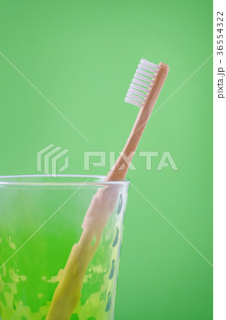 alternative wooden toothbrush in a glass on green 36554322