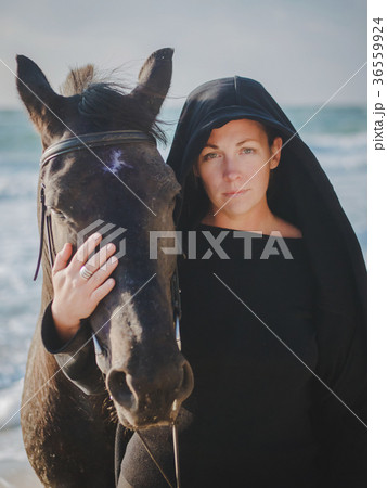 woman stroking and hugging horse at sea beach 36559924