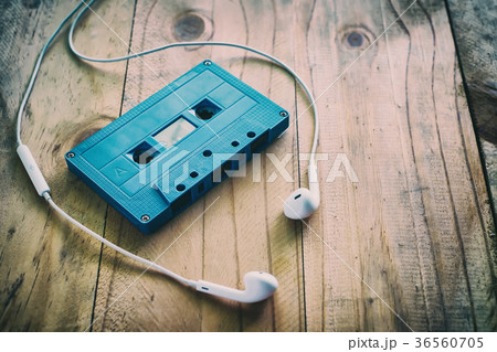 Cassette tape and white earphone on wooden table 36560705