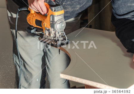 Electric jigsaw cuts chipboard Electric jigsaw cuts chipboard 36564392