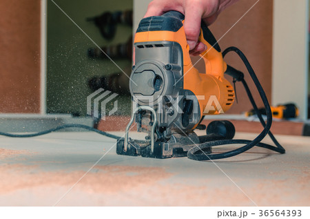 Electric jigsaw cuts chipboard Electric jigsaw cuts chipboard 36564393