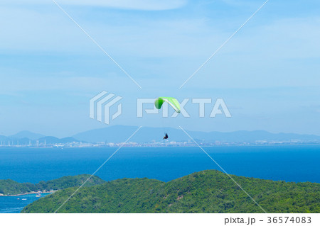 Paragliding flying through the sea and sky. 36574083