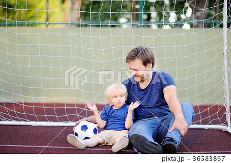 Little boy and his middle age father having fun playing a soccer/football game on summer day Little boy and his middle age father having fun playing a soccer/football game on summer day 36583867