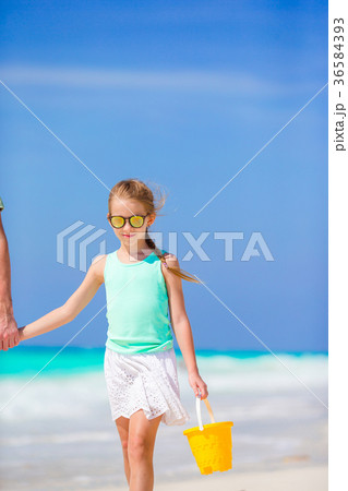 Little girl with beach toys walking along the sea Little girl with beach toys walking along the sea 36584393
