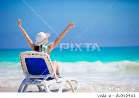 Young woman in hat on a tropical beach looking on 36585433