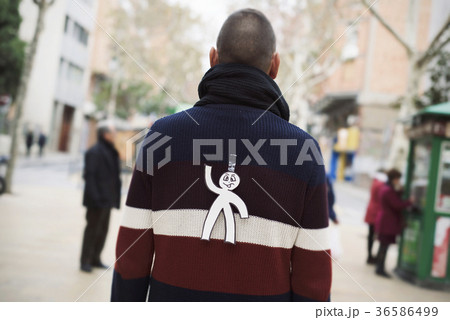 young man with a paper man attached to his back 36586499