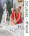 Mom and daughter in Christmas costumes are sitting under snow 36587162