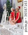 happy mom and daughter in Christmas costumes are sitting under snow 36587163