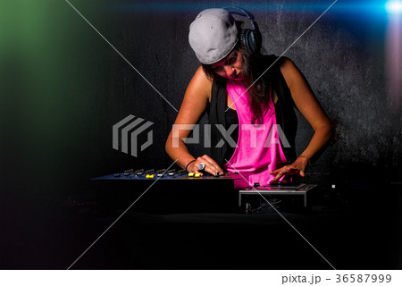 Glamorous girl deejay at work mixing sound on her console at a p 36587999