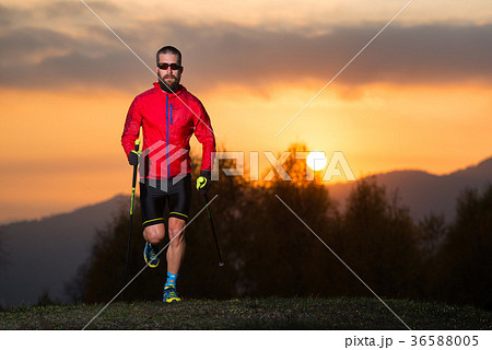 Man athlete practicing nordic walking in the mountains at sunset Man athlete practicing nordic walking in the mountains at sunset 36588005