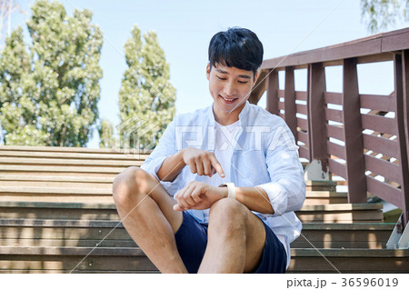 Young guy take a relax in park, sit on green grass and walking in around. 015 36596019