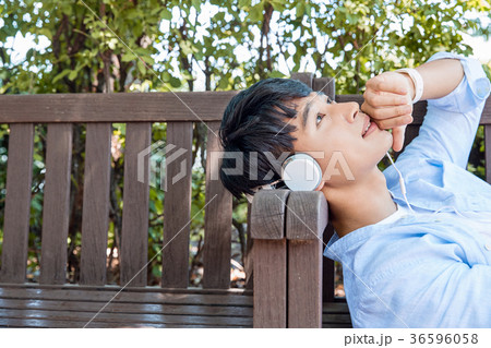 Young guy take a relax in park, sit on green grass and walking in around. 082 36596058