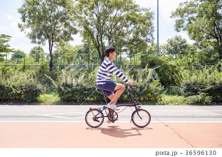 Young guy take a relax in park, sit on green grass and walking in around. 107 36596130