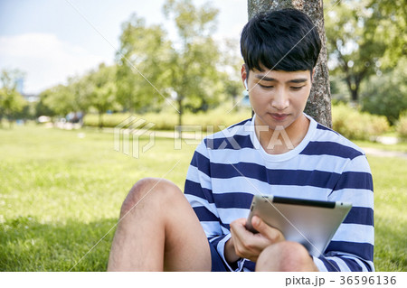 Young guy take a relax in park, sit on green grass and walking in around. 119 36596136