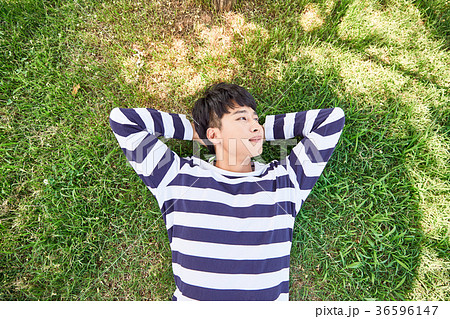 Young guy take a relax in park, sit on green grass and walking in around. 126 36596147