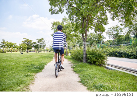 Young guy take a relax in park, sit on green grass and walking in around. 111 36596151