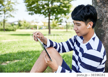 Young guy take a relax in park, sit on green grass and walking in around. 133 36596161