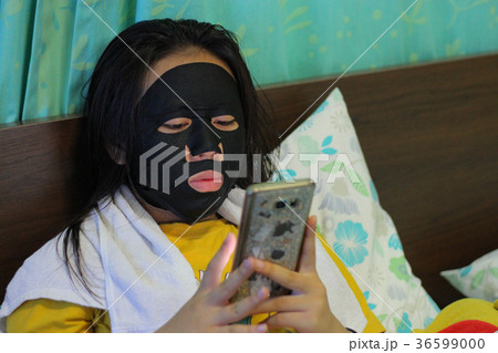 young beautiful woman is having a black mask on her skin.Skin he 36599000
