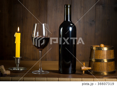 Pouring red wine into wineglass from green bottle 36607319