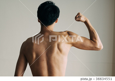 力こぶをつくる若い日本人男性 後ろ姿の写真素材